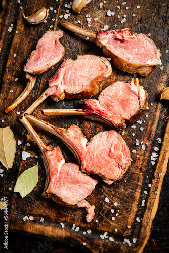 Rack grilled lamb on a cutting board with bay leaves. 