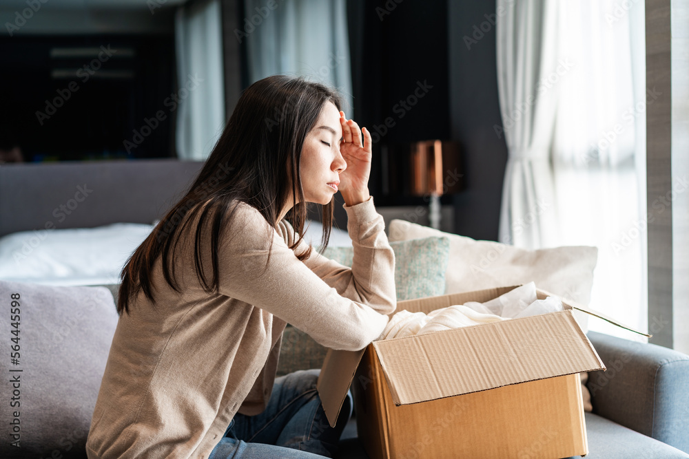 Dissatisfied young woman unpacking parcel at home received damaged and wrong online shopping order Dissatisfied young woman unpacking parcel at home received damaged and wrong online shopping order