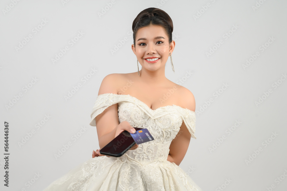Young asian beautiful bride posting with credit card and smartphone in hand Young asian beautiful bride posting with credit card and smartphone in hand