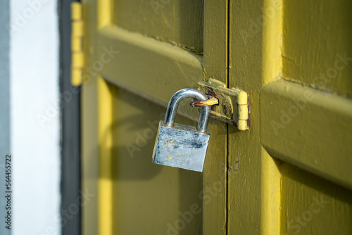 Yellow wood door closed with rusty padlock. Security concept.
