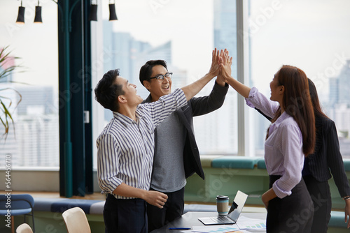 businesspeople giving high five pose and celebrating success at work in the office