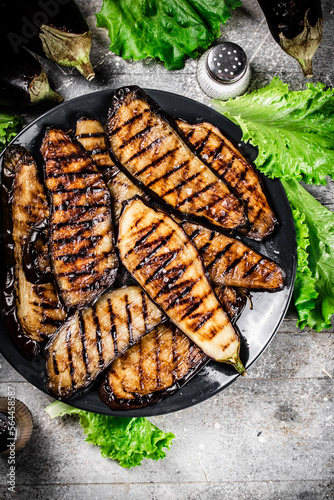 Grilled pieces of eggplant on a plate of lettuce. 