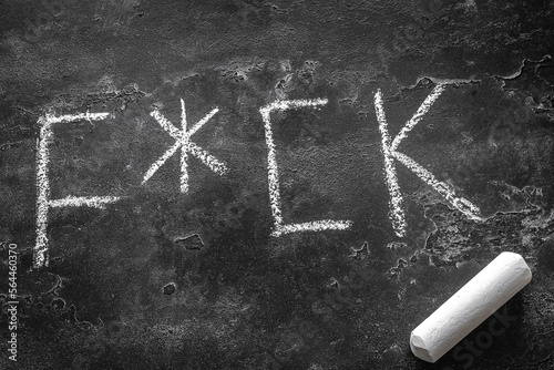 obscene word written in chalk on a black background photo