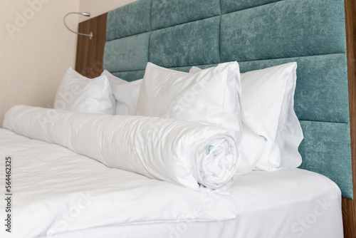Interior with blue white colors. Bedroom with bed, white bedding. White pillows, duvet and duvet case on bed with blue headboard. relax comfortable apartment. selective focus