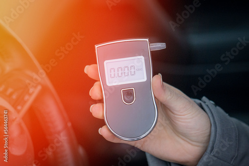 a woman with a breathalyzer in the car, testing for alcohol 