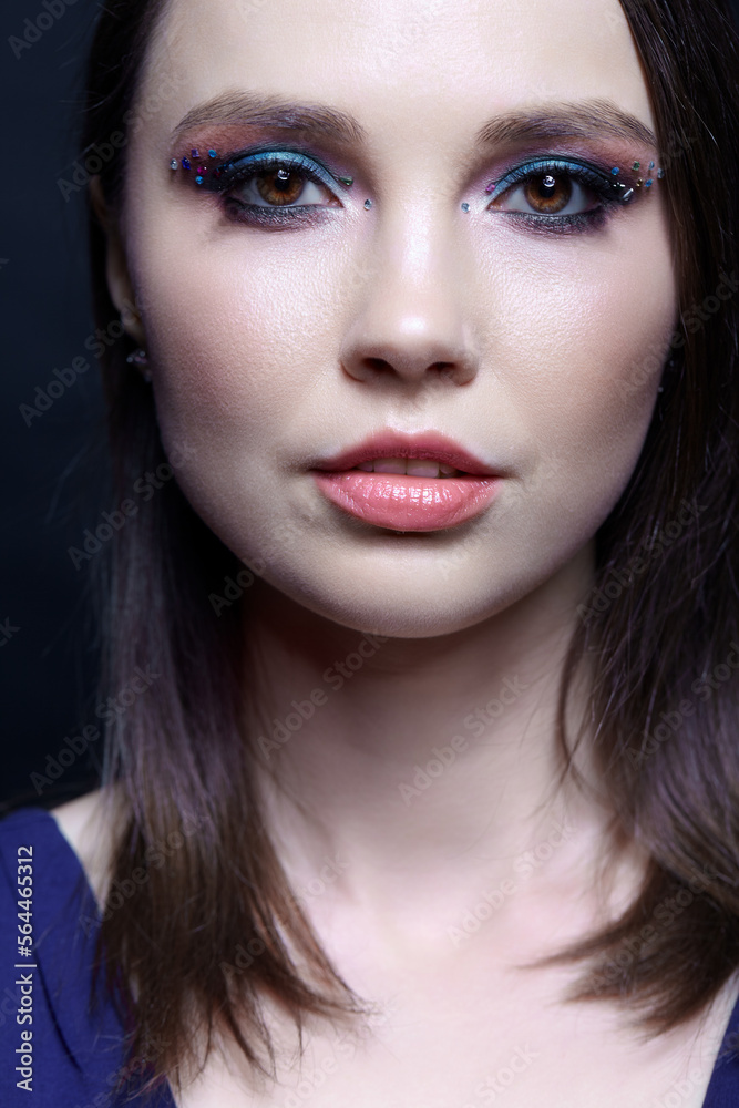 Portrait of beautiful brunette woman with blue eye shadow make up and rhinestones.