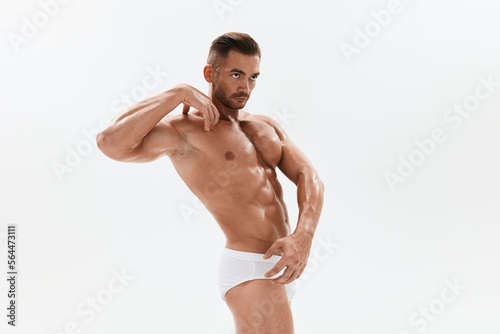 Man athletic body bodybuilder in briefs with naked torso abs full-length in the background  fitness classes. Advertising  sports  active lifestyle  competition  challenge concept.