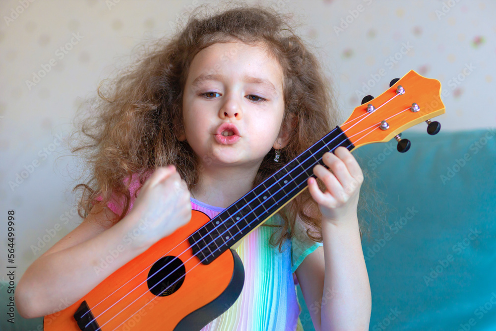 little cute girl playing guitar ukulele and singing song. musical