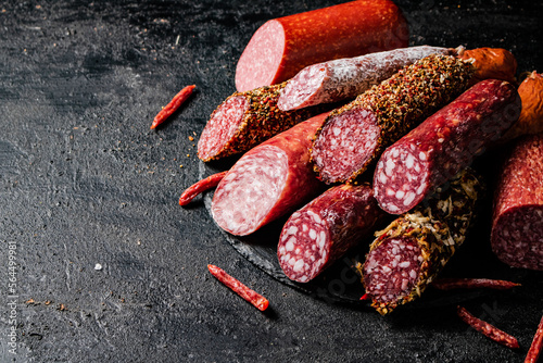 A variety of types of salami sausage with dried chili peppers on the table. 