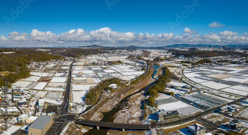 Aerial view of snow covered rice fields in Japanese countryside on sunny winter day