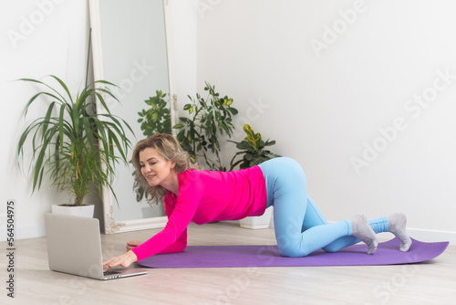 Attractive young woman doing yoga stretching yoga online at home. Self-isolation is beneficial, entertainment and education on the Internet. Healthy lifestyle concept