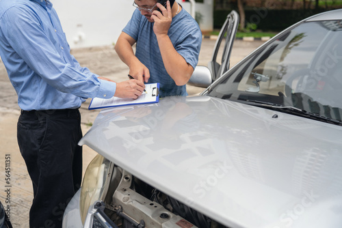 Insurance officer writing Insurance Claim Report on clipboard while insurance. Man and Insurance agent claim process after car crash