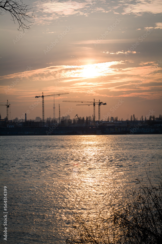 Tower cranes on abandoned area landscape photo. Beautiful nature scenery photography with sunset, river on background. Idyllic scene. High quality picture for wallpaper, travel blog, magazine, article