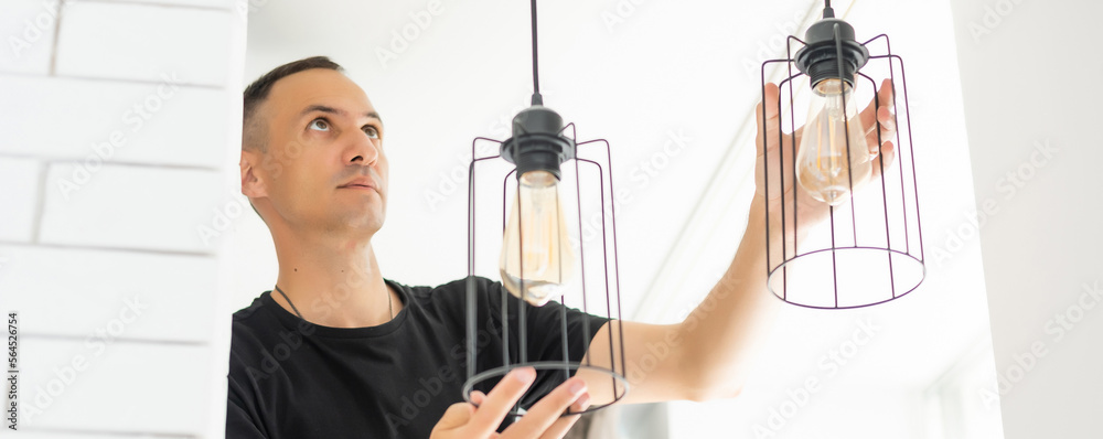 Worker repairing lamp on stretch ceiling indoors