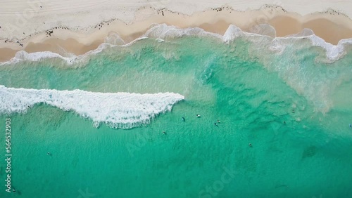 Top down vertical view of surfers catching a wave at Scarborough Beach in Perth