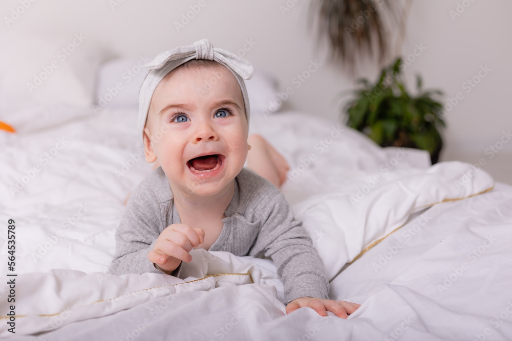 happy cute baby girl 7 months old at home on the bed playing with educational toys. Child development. Comfort at home happy cute baby girl 7 months old at home on the bed playing with educational toys. Child development. Comfort at home