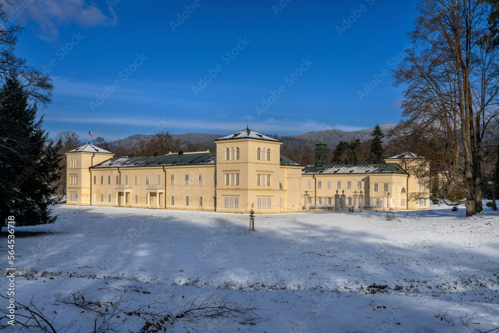 State Classicist chateau Kynzvart in winter under snow and with blue sky - castle is located near the famous west Bohemian spa town Marianske Lazne (Marienbad) - Czech Republic