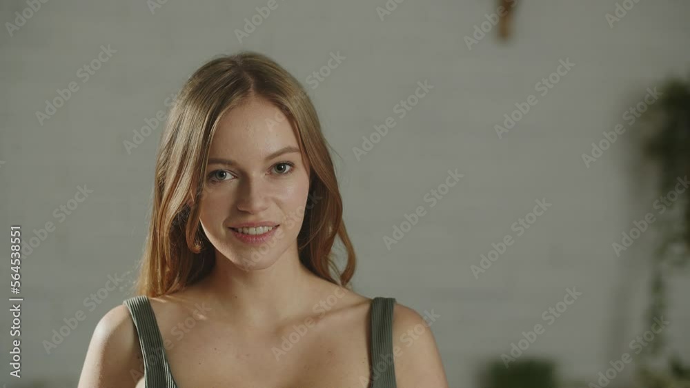 Portrait of beautiful european girl smiling to camera. Indoor footage of attractive young woman expressing happiness Portrait of beautiful european girl smiling to camera. Indoor footage of attractive young woman expressing happiness