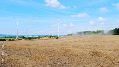 Tractor working in the field against the backdrop of rotating windmills
