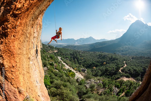Rock climber descends from the route, the climber hangs on a rope, a rock in the form of an arch, climbing routes in a cave