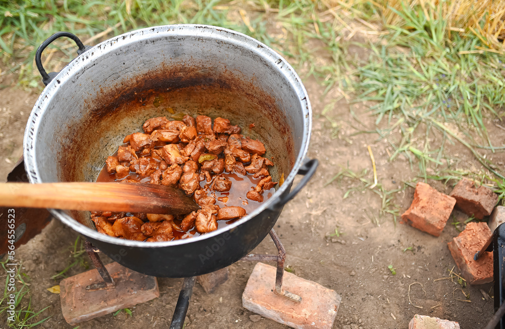 Cooking in an old cast iron cauldron on wood fire in the middle of nature. Traditional tasty way to cook in campfire. Cooking in an old cast iron cauldron on wood fire in the middle of nature. Traditional tasty way to cook in campfire.
