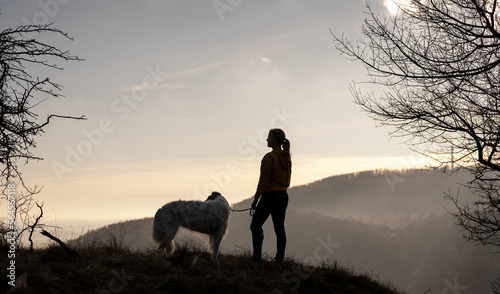 Woman standing with her dog on top of the hill - silhouette 