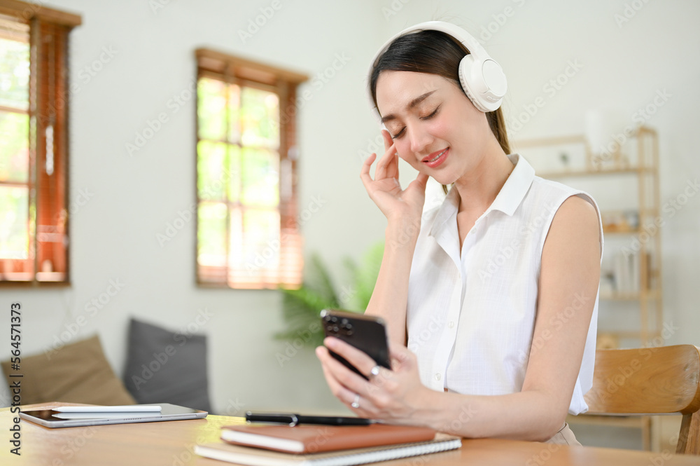 Relaxed Asian woman wearing headphones, enjoying with the music in her living room. Relaxed Asian woman wearing headphones, enjoying with the music in her living room.