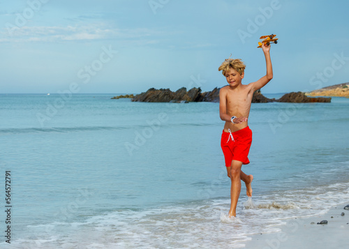 Young boy run holding toy model of plane on the ocean beach