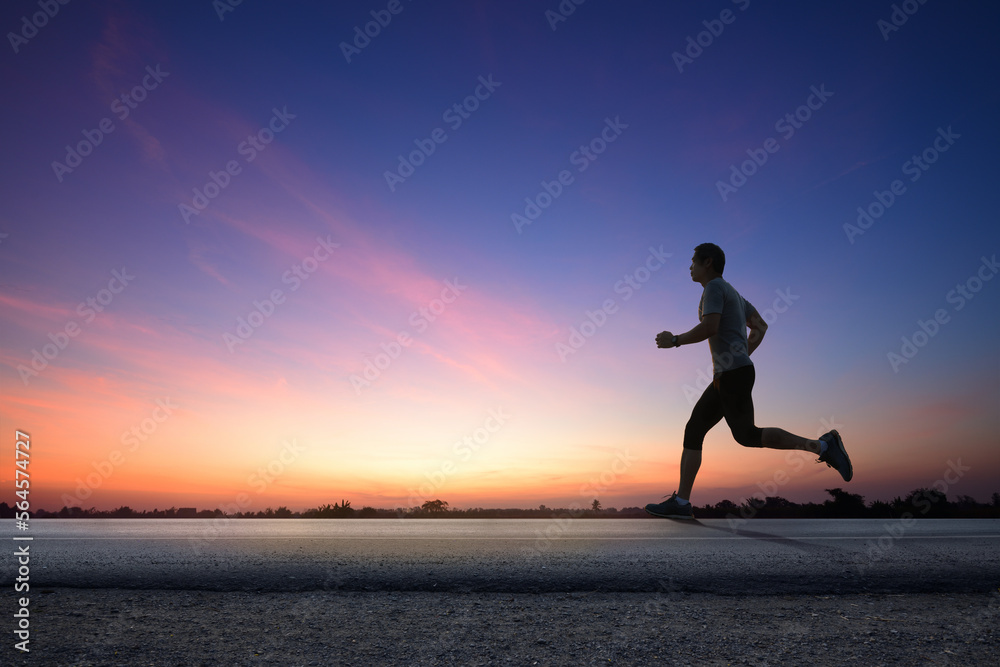 Silhouette view of a man jogging on road with dawn sky background.