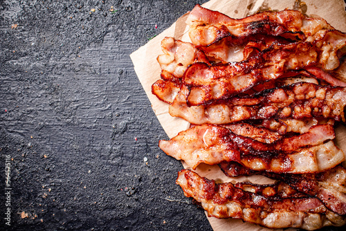 Quadro em tela Pieces of fried bacon on paper.