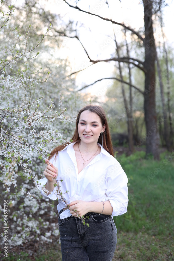 beautiful girl in a white shirt near a blooming tree. Beautiful warm spring and blossoming trees beautiful girl in a white shirt near a blooming tree. Beautiful warm spring and blossoming trees