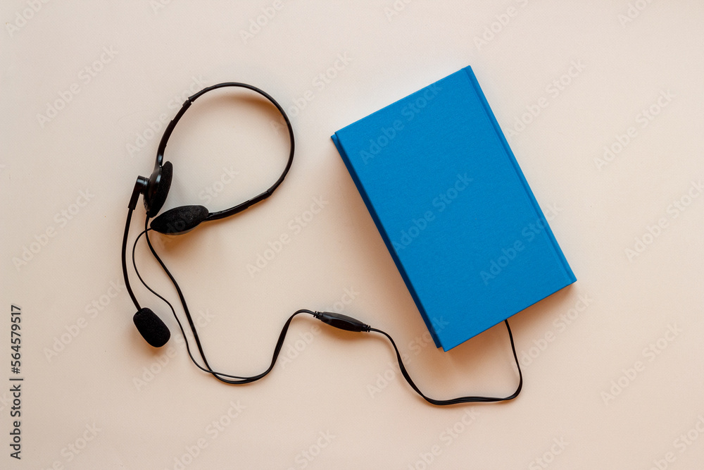Audiobook or podcast concept with book and headphones nearby Audiobook or podcast concept with book and headphones nearby