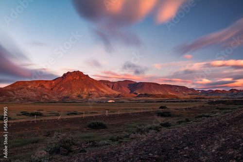 Long exposure landscape of iceland red rocky mountain with blue sky, blurry orange clouds and lowland on the foreground
