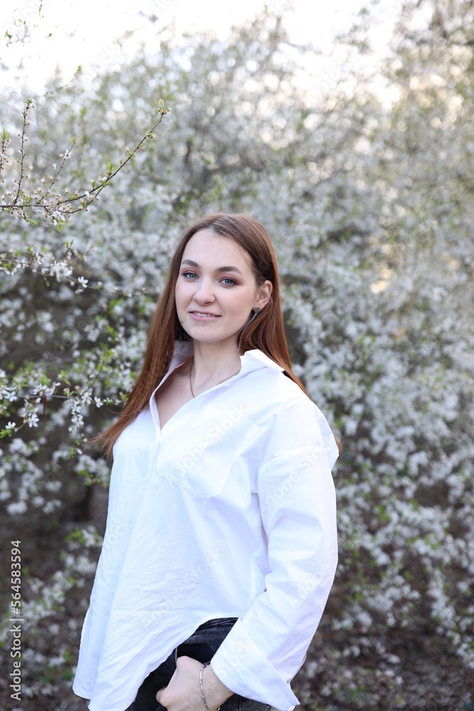 beautiful girl in a white shirt near a blooming tree. Beautiful warm spring and blossoming trees beautiful girl in a white shirt near a blooming tree. Beautiful warm spring and blossoming trees