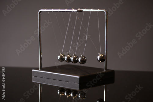 Closeup metal Newton cradle placed on gray background as representation of momentum concept