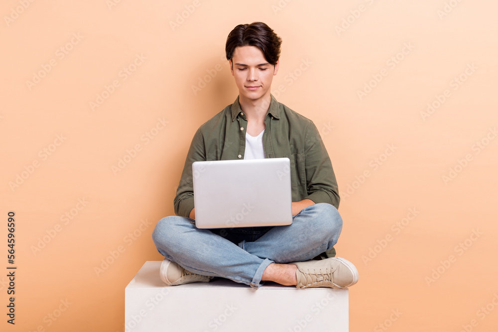 Full body size photo of attractive man wear khaki shirt typing browsing information laptop internet conference isolated on beige color background Full body size photo of attractive man wear khaki shirt typing browsing information laptop internet conference isolated on beige color background