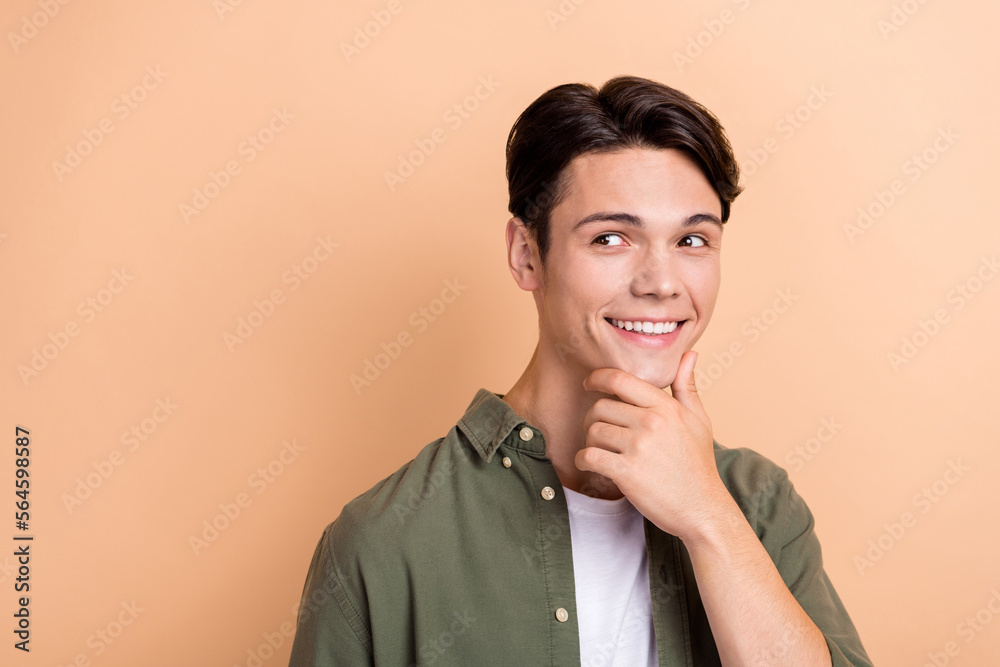 Portrait of positive smart minded person arm touch chin look empty space isolated on beige color background Portrait of positive smart minded person arm touch chin look empty space isolated on beige color background
