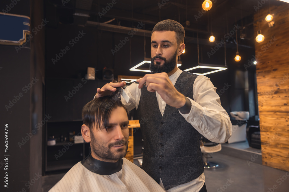 Hairdresser making a new haircut to the male client Hairdresser making a new haircut to the male client