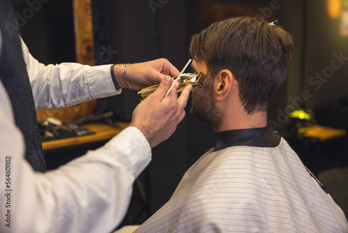 Barber carefully trimming the clients beard