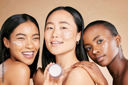 Beauty, portrait and face cream by diverse women in studio for wellness or grooming on brown background. Friends, skincare and skin lotion for girl group with different, facial and product isolated photo