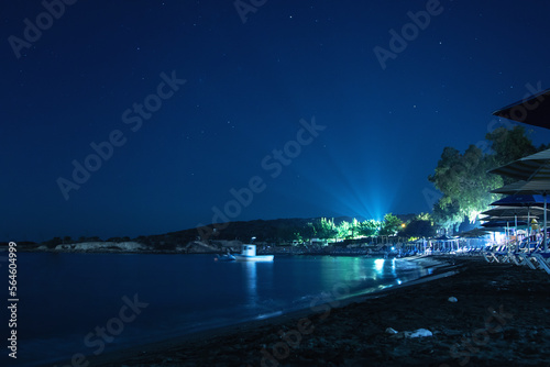 Coastal beach resort at night with rays of lights and sunbeds