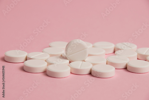 Many white pills macro on pink paper background with space for text photo