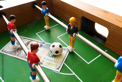 Table football game with US dollar bills scattered around it, alluding to a betting concept