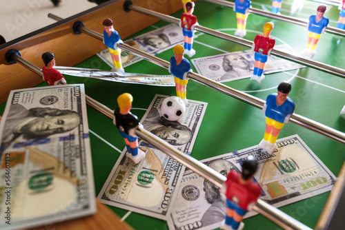 Table football game with US dollar bills scattered around it, alluding to a betting concept