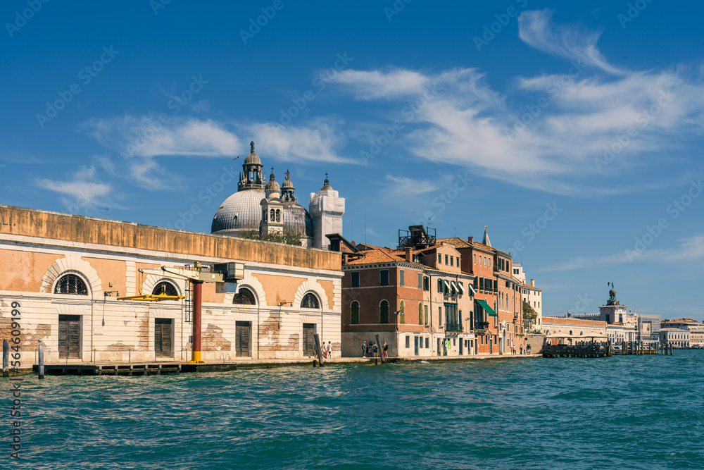 Real old houses along the sea in the street of Venice along the Grand Canal on a sunny day, a seagull in the blue sky, a cargo crane at the edge of the sea, the main sea street of Venice, Italy travel