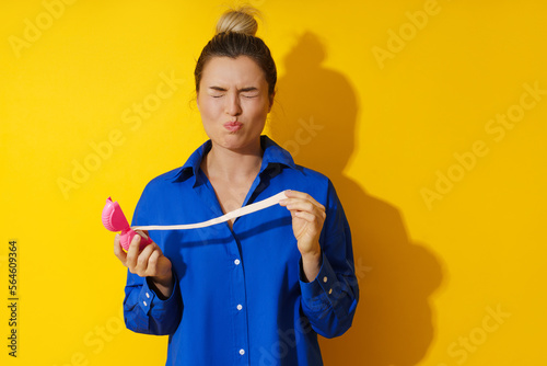 Young woman tasting sour chewing gum against yellow background