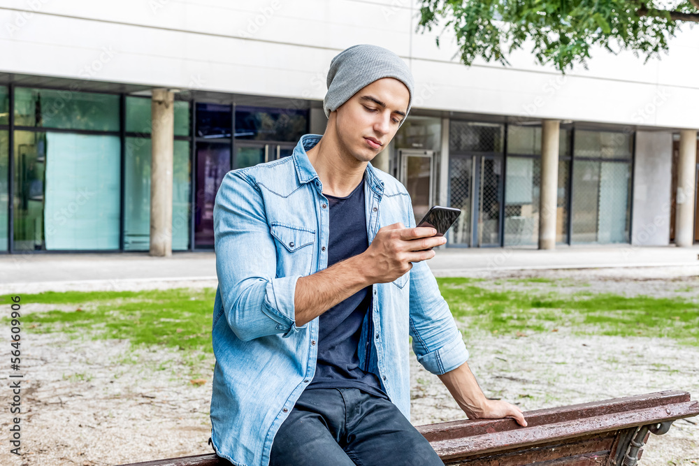 Attractive young smiling man using phone in a public park Attractive young smiling man using phone in a public park