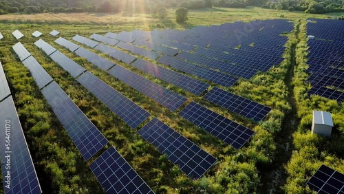 Aerial view of power station of solar panels on the green field in sunset.