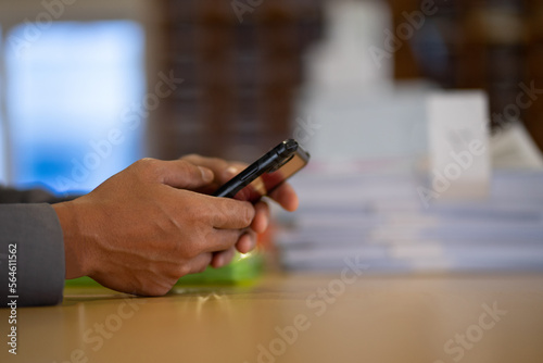 Hands of a man in a gray suit talking on a mobile phone at a desk