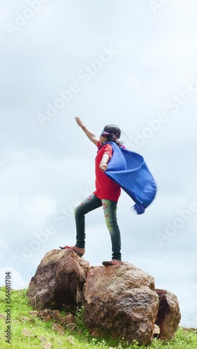 vertical shot girl with superman custume and enjoying by imagining at mountain - concept of childhood lifestyle, inspiration and adventure lifestyle photo